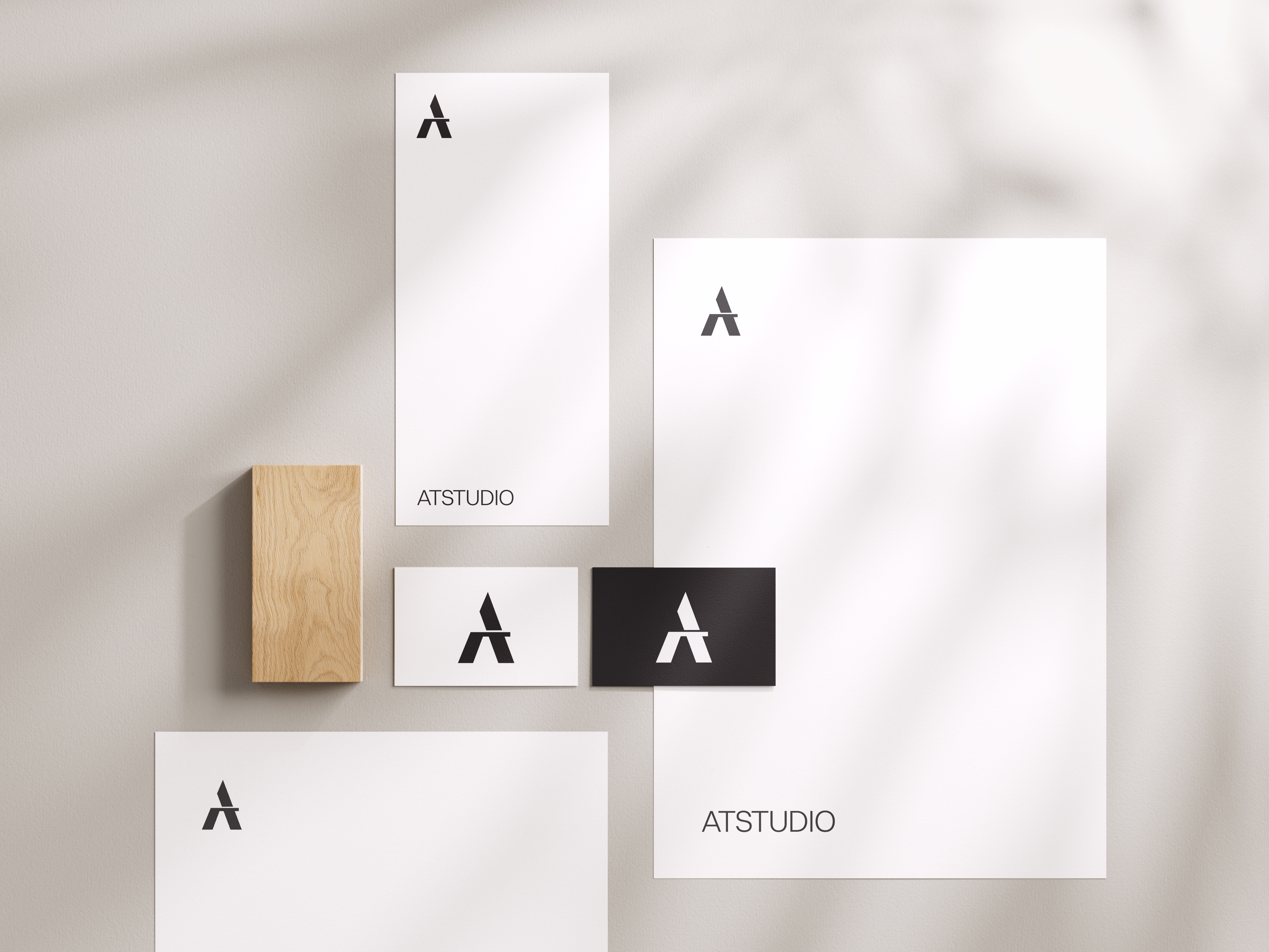 A mockup of AT Studio logo design in different size paper from business card to A4 paper.